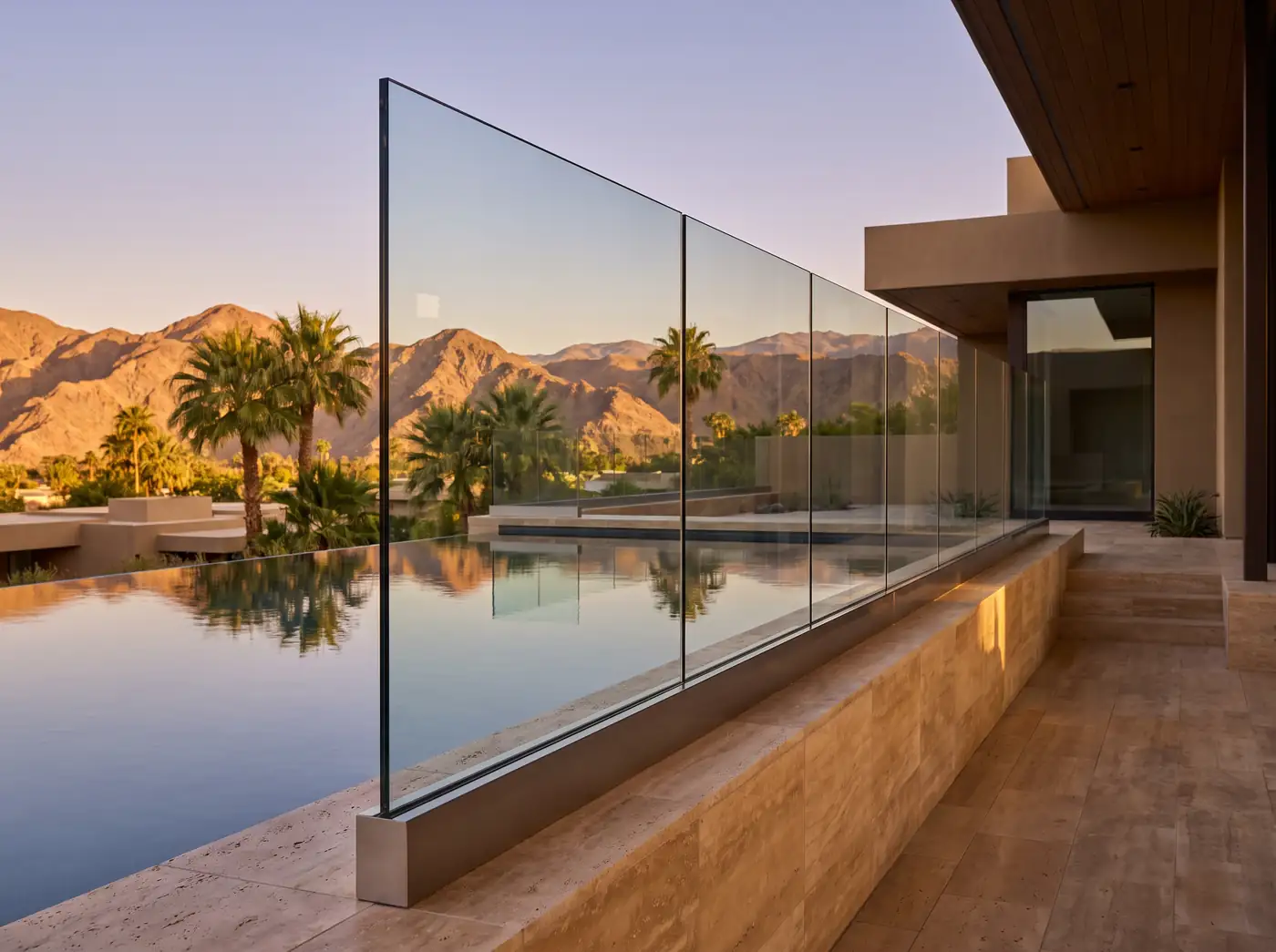 Frameless glass railing with a slim base shoe along a desert pool deck