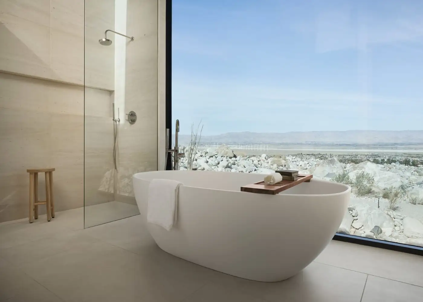Frameless shower enclosure beside a freestanding tub and desert window