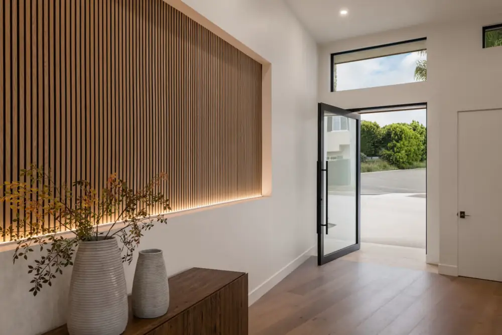 Glass pivot entry door beside a slatted timber wall